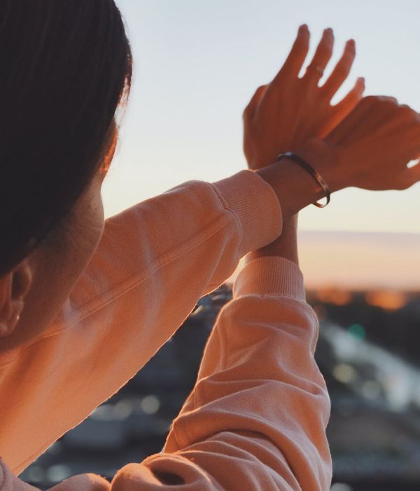 Person stretching gracefully outdoors in a field during sunrise.